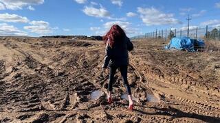 A girl in very high-heeled shoes walks on a super dirty road so that her shoes turn into pieces of earth very quickly