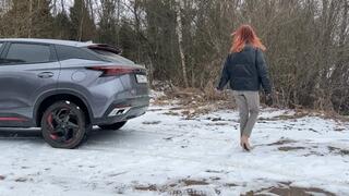 A girl in cute pink boots walks through the spring snow in the forest, her shoes slip on this uneven path