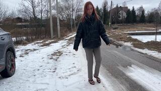 girl in flat sandals walking through winter forest, her sandals slipping on ice and snow, and snow falling on her toes