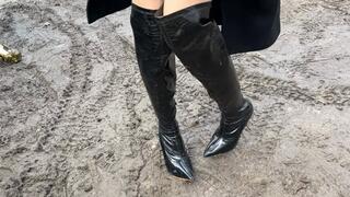 A girl in boots walks through the mud and gets her leather boots dirty, after that she kneels in her boots to get her boots even more dirty