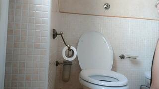 A beautiful woman sitting on the toilet administering an enema