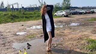 A girl in high-heeled shoes walks through the mud and tramples on her shoes, puts them on her dirty stockings
