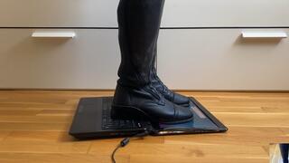 Leather riding boots crushing a laptop into pieces