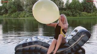 Alla floats on an inflatable lounger on the lake and makes a B2P yellow balloon