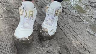 A girl in fashionable snow-white sneakers He walks on slippery, sticky mud and gets his hands dirty and crush her sneakers