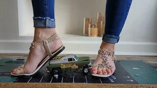 Priscilla toy car crush she crushes a 50s Chevy van & Ferrari in sandals close ground view