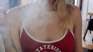 European girl smoking a cigarette at home in streetwear outfit