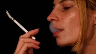 Eve, the glamorous blonde, enjoys her cigarette in mesmerizing slow motion.