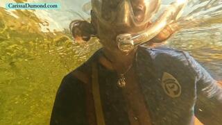 Carissa in vintage wetsuit at edge of a clear spring and the dark river