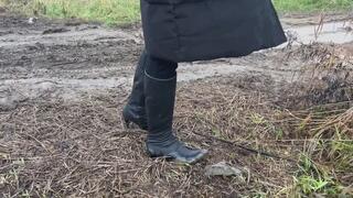 A girl in high-heeled boots walks through mud in bad weather and slides on hills (short version)