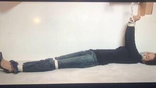 Tape-gagged brunette Gia Mancini lay stretched out and writhing on the floor with her arms tied overhead to a wooden bar!