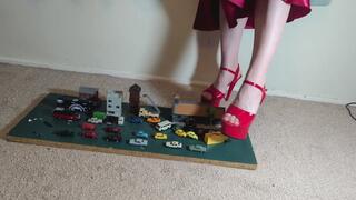 Giantess Lily Kink toy car crush of tiny cars, buses, trucks & buildings in big mega red heels and stomping the bits in a box high right view