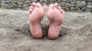Mature woman buried on the beach with her feet sticking out (1)