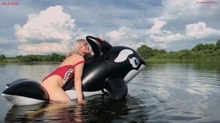 Alla is riding a black inflatable whale on a lake and suddenly the inflatable whale pops