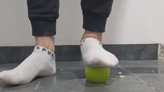 Apples being crushed by male feet in white socks