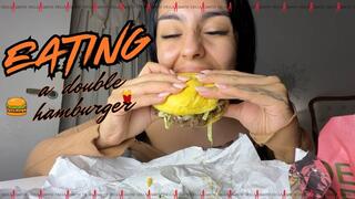 Eating a double hamburger.
