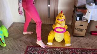 a girl barefoot in red tight jeans tramples two inflatable dinosaurs, puts her weight on them, presses foot fetish crash fetish legs jeans