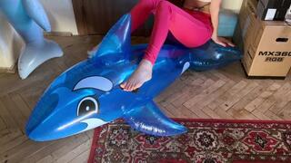 a girl in red tight jeans tramples two inflatable whales, puts her weight on them, presses foot fetish crash fetish legs jeans