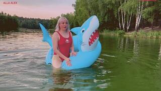 Swimming on a large inflatable shark ring on a lake