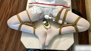 ADM58-An Asian girl in white stockings, legs spread apart, a vibrating toy strapped to her legs, experiencing a vibrating orgasm.