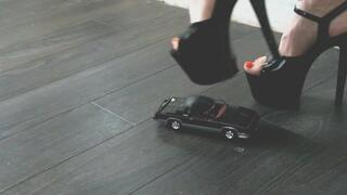 Giantess goddess Charlie Caroline Crushes a 1983 Oldsmobile Hurst in mega black heels with painted toenails close upper right view