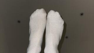 Male athlete takes off white socks after a long day and a good workout.