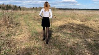 a cute girl walks across the field in stockings and high-heeled shoes, the road is very difficult, she twists her leg, falls, tears her stockings, feels terrible pain