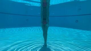 Wrist self-bondage in the resort pool in a rainbow bikini