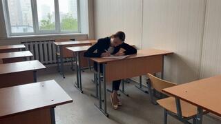 a girl sits at lesson in school and plays with her feet and ballet shoes