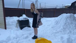 girl walks barefoot in the snow and slides down the hill