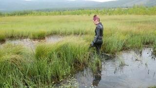 Pretty girl in leather leggings discovers swamp mud, walks, falls and gets stuck in swamp mud
