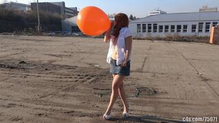 Titi blowing giant orange balloon outdoors (4K quality)
