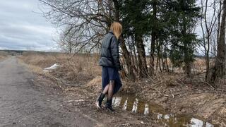 girl in short high-heeled boots walks through deep mud and puddles looking for a way home