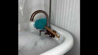 Harmony scrubs her feet in soapy bubbles in the bathtub