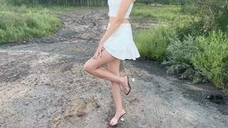 A girl in high-heeled sandals walks on slippery mud and slides (re-realize)