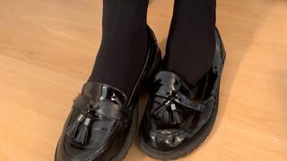 Shoeplay and dangling in black flat loafers and Doc Marten shoes with black pantyhose