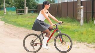 Pretty girl in high heels riding a bike and watering flowers