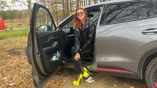 A girl in very high-heeled shoes is playing with a car in the woods, she really likes to pedal and play with shoes