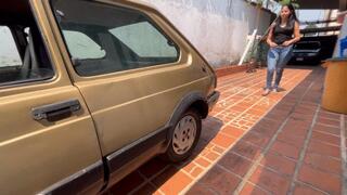 Kaena in jeans and flip flops tries to start the fiat 147