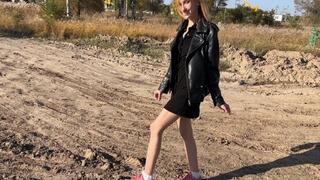 A girl in sneakers and white socks walks deep in the mud, she takes off her sneakers so that her snow-white socks turn brown