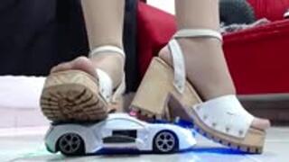 crushing a police toy car robot with nylons and hard soled wooden sandals