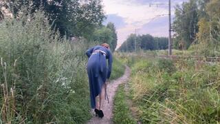 A girl walks in the park in high-heeled shoes and talks on the phone, she is so engrossed in the conversation that she does not notice where she steps on her heels