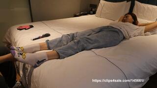 Asian girl's bare feet in cotton socks are tickled