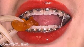 Crushing gummy bears with my vampiric sharp white teeth (with braces and long nails)